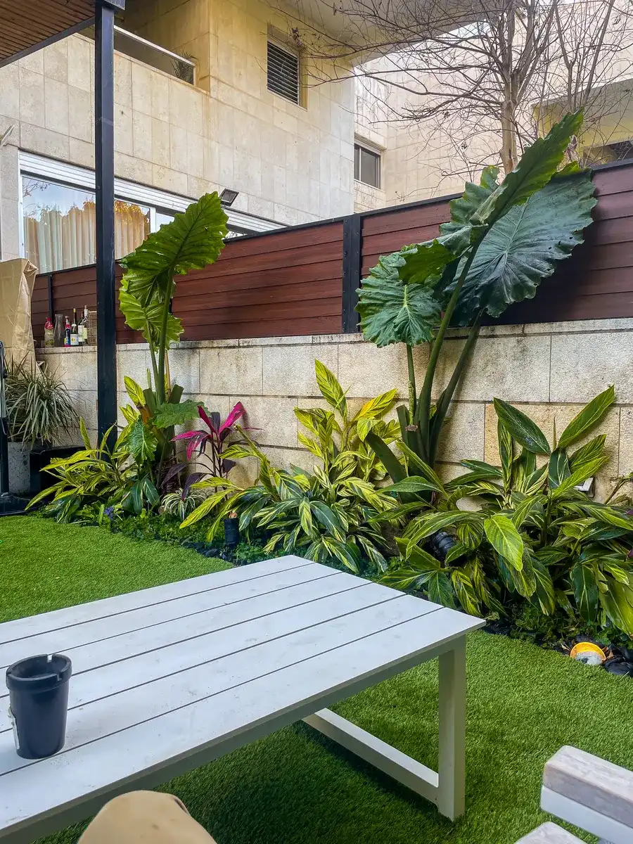 פינת ישיבה על דשא מול ערוגה טרופית בבית פרטי בצהלה