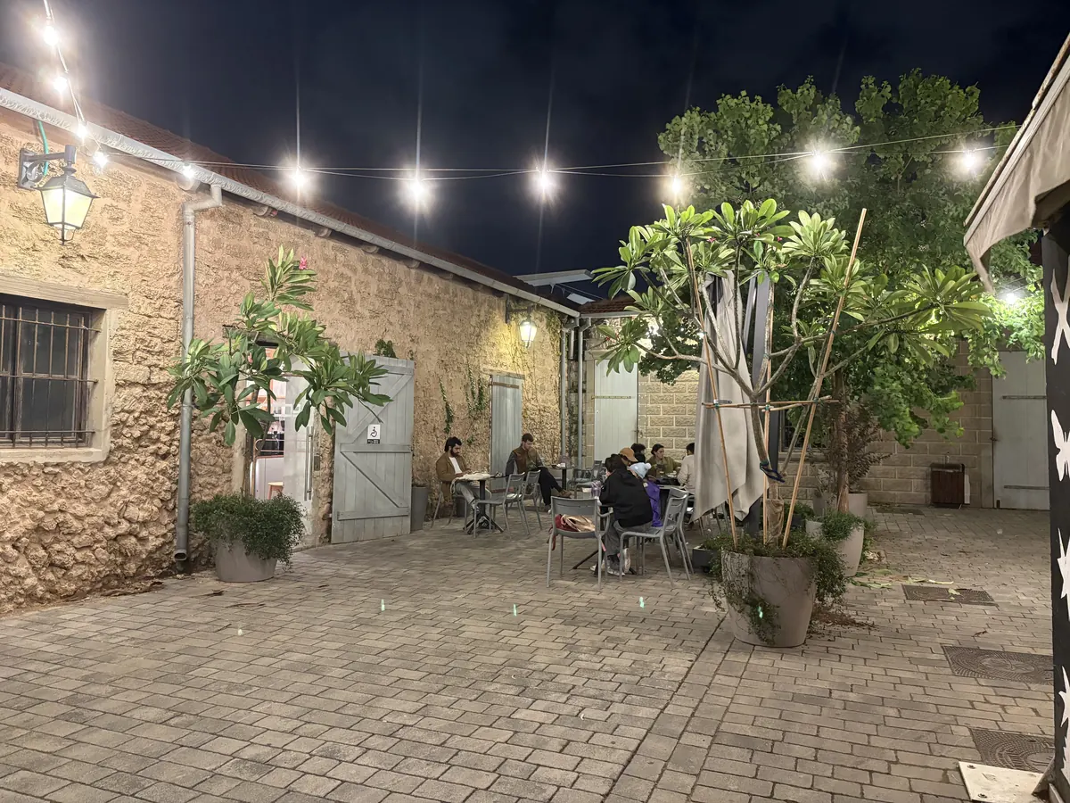 חצר בית הקפה בלילה: שרשראות תאורה ומבני אבן