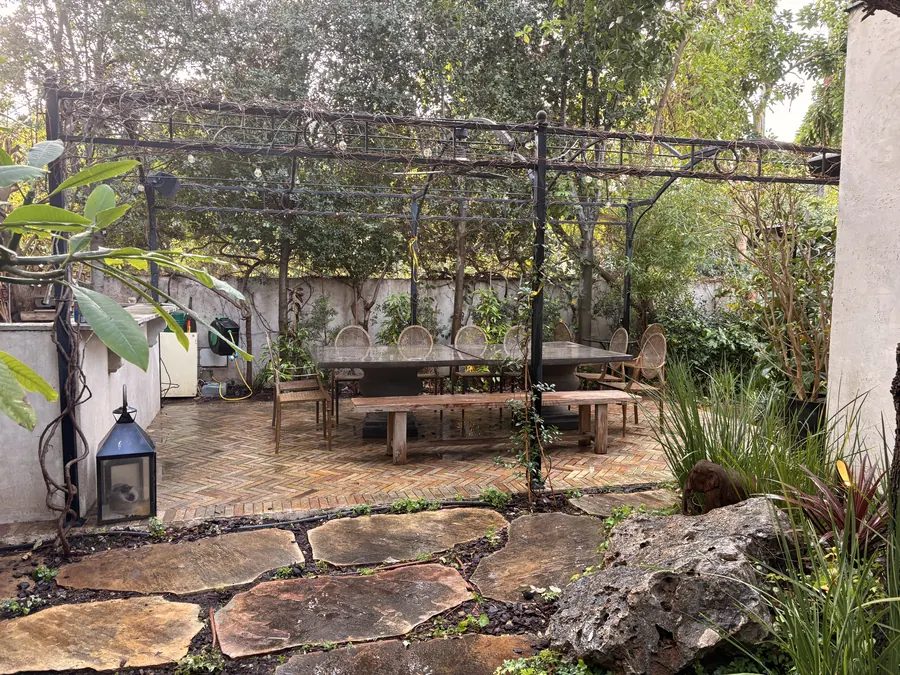 פינת אוכל תחת פרגולת ברזל שחורה עם מטפסים